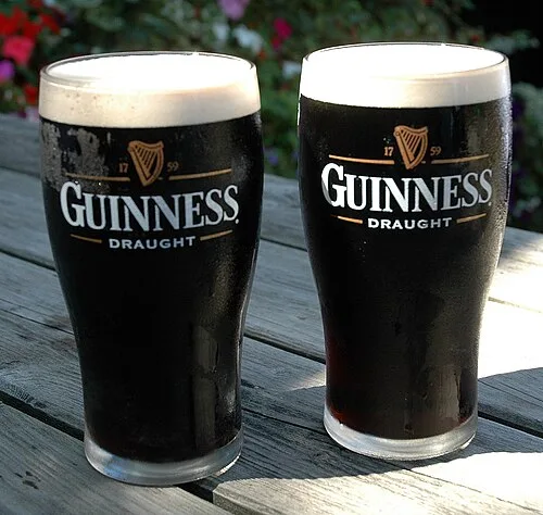 Guinness Draught 로고가 있는 전용 잔에 따른 흑맥주 두 잔